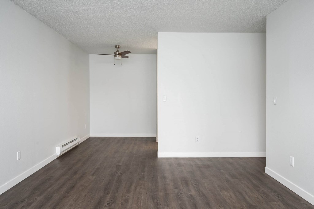 an empty living room with white walls and a ceiling fan